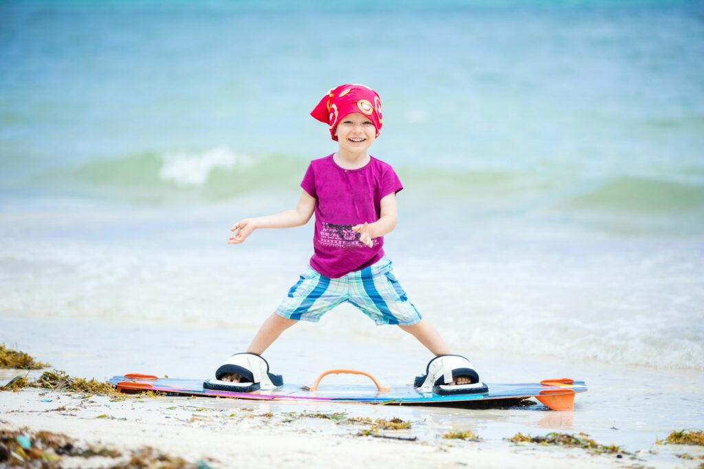 Young boy standing on board for kitesurfing and smiling Kitesurfing Lessons for Kids in Dubai: Fun and Safe Options